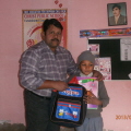 Principal Amin Issac presents a child with new school supplies.